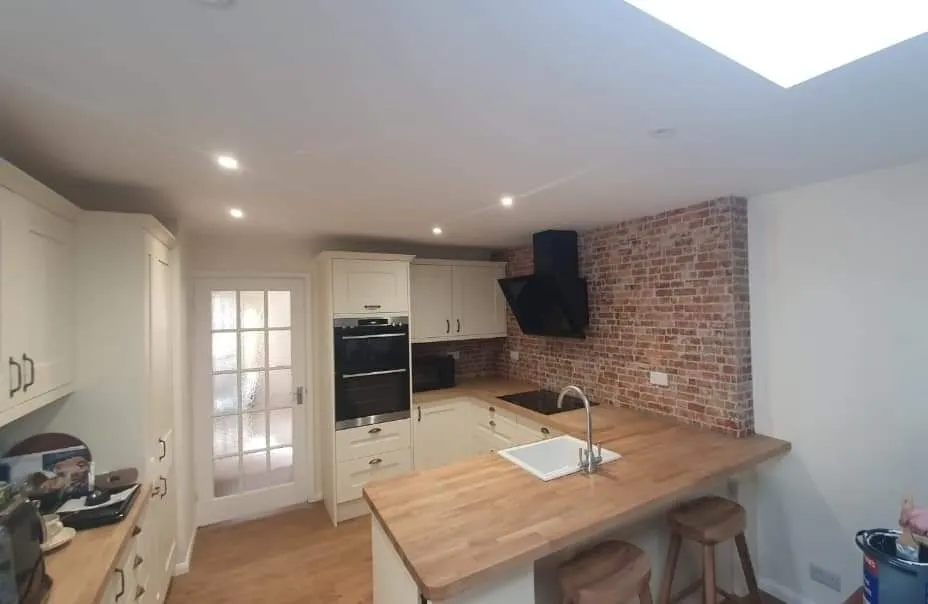 A kitchen with a wooden counter top next to a brick wall.